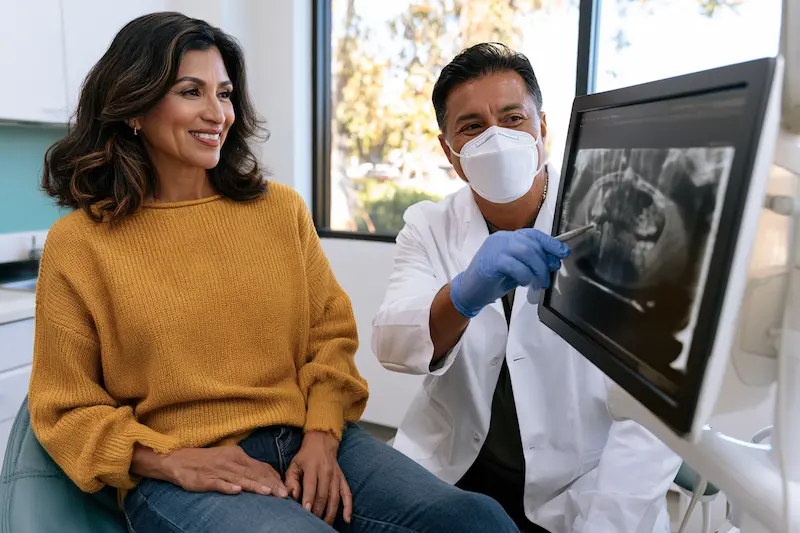 Especialista en rehabilitación oral explica a una paciente su radiografía panorámica durante la valoración
